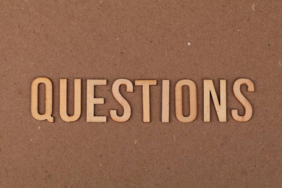 Wooden letters spelling the word "QUESTIONS" on a cardboard background, providing a neutral copyspace.