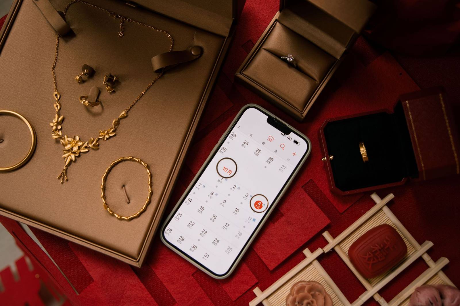 A stylish flat lay featuring gold jewelry alongside a phone displaying a calendar, perfect for special occasion planning.