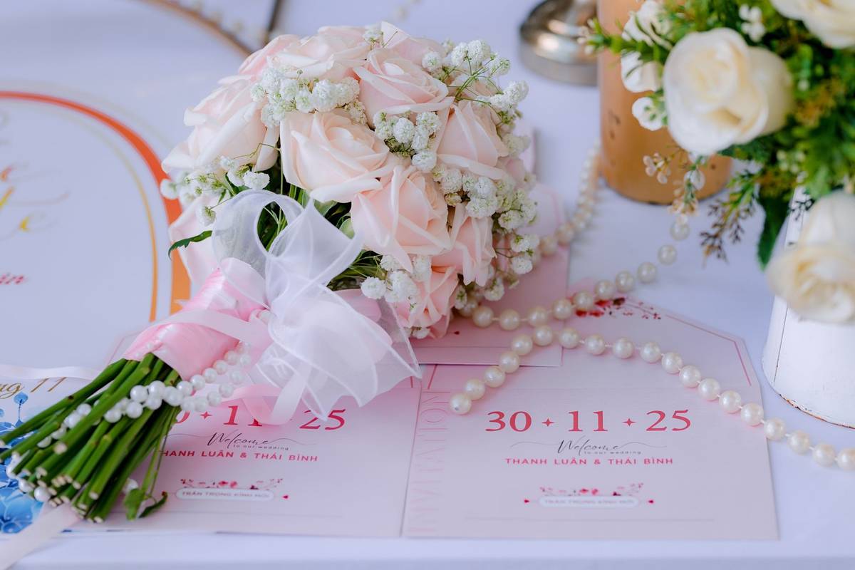 Delicate pink rose bouquet with wedding invitations on a table, perfect for a romantic wedding setting.