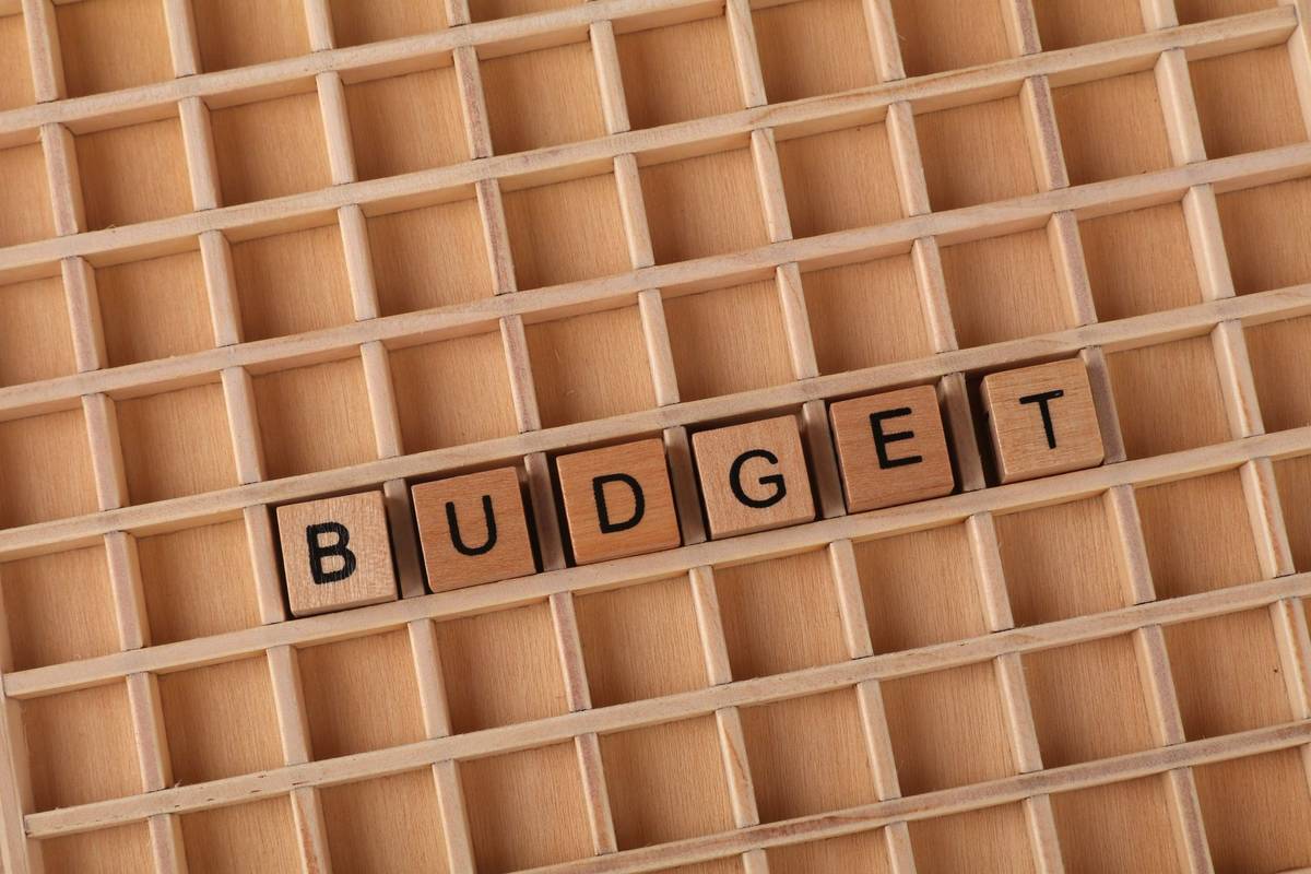 Wooden letter tiles spelling 'budget' on a wooden grid background, symbolizing finance and planning.