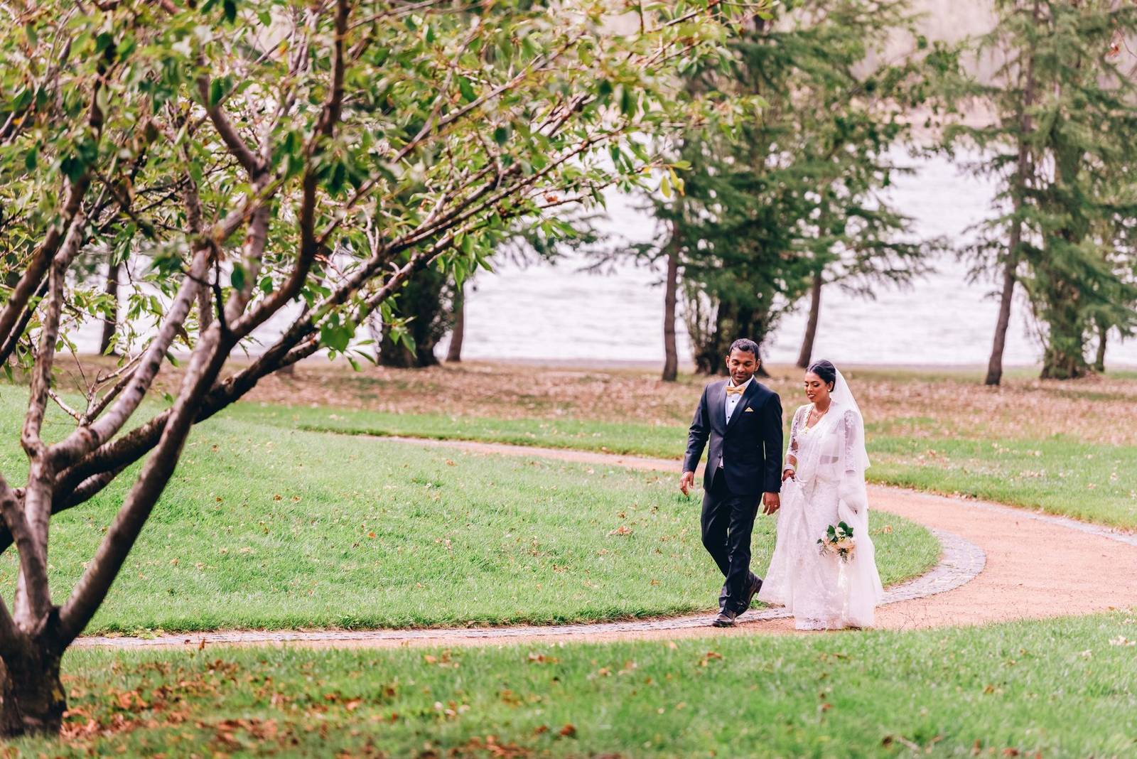 Bride and groom walking along a pathway in a scenic park in Canberra, Australia.