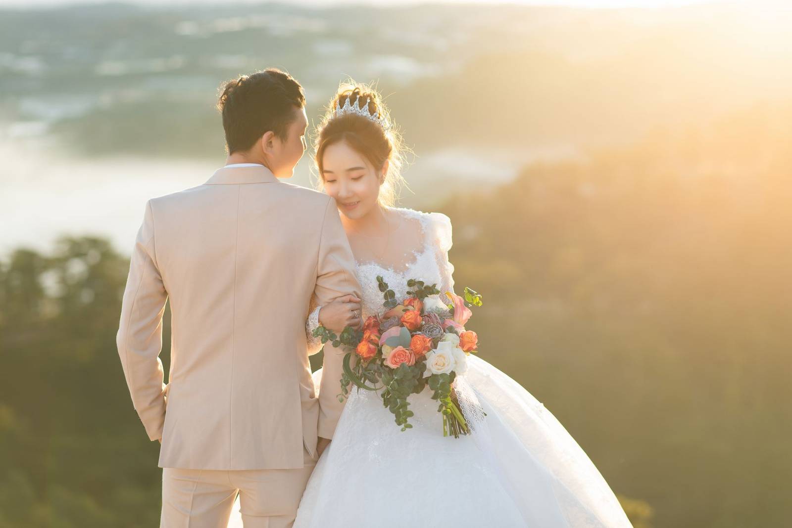 Bride and groom embracing with a floral bouquet at sunset, capturing their love on a summer wedding day.